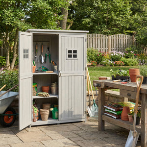 Outdoor storage shed filled with gardening tools and supplies in a garden setting.