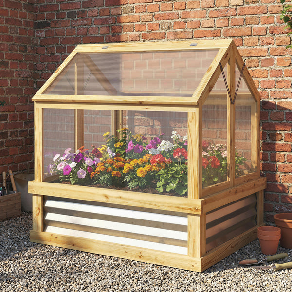 Wooden cold frame with plants against a brick wall